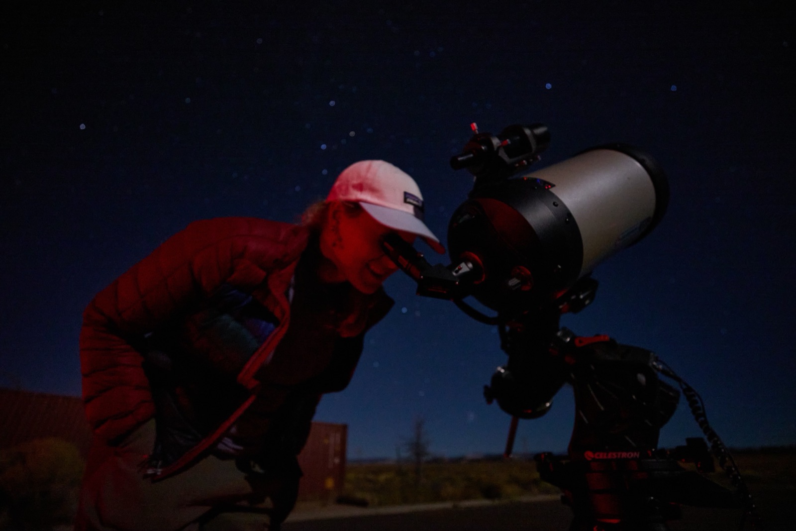A guest wearing a red headlamp looks through a Celestron telescope eyepiece under Bryce Canyon's dark sky
