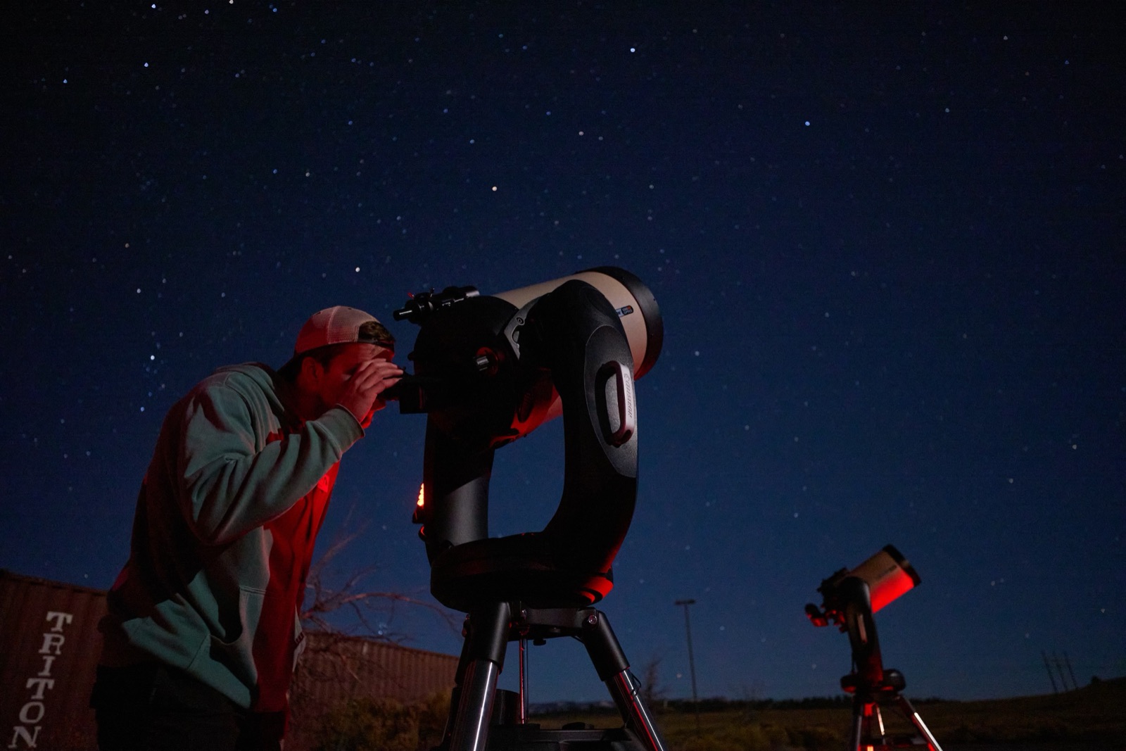 A guest looking through a telescope eyepiece under a star-filled night sky near Bryce Canyon