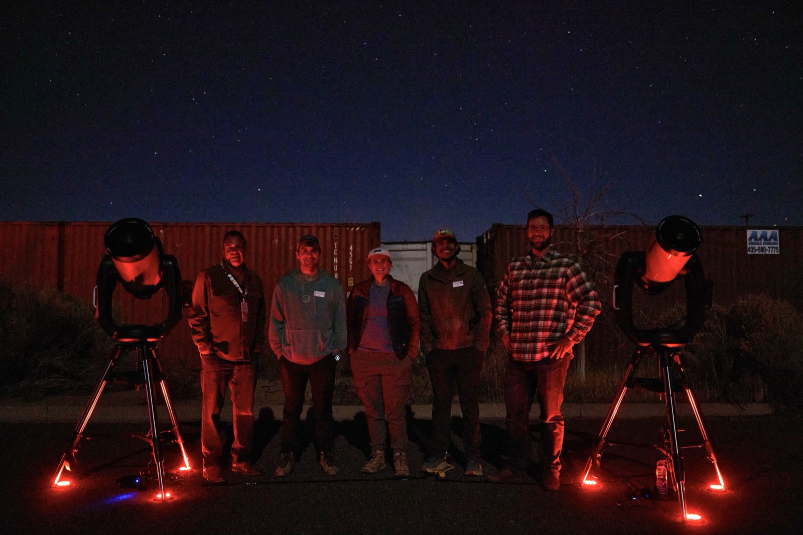 A smiling tour group standing with telescopes after a Bryce Canyon stargazing tour